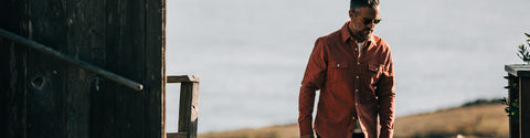 Our guy in a rusty colored Yosemite shirt, walking up from the beach to a wooden structure with handrail.