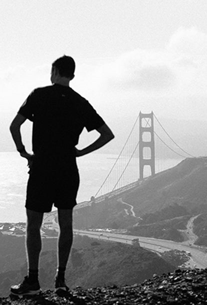 Man pausing on run to look over Golden Gate Bridge and San Francisco Bay from the Marin Headlands