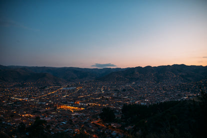 A city under a clear sky at dusk, with orange city lights highlighting the streets and roads.