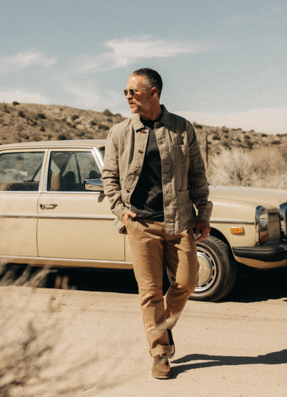 Model walking in front of a vintage Mercedes in The Organic Cotton Tee in Faded Black, The Ojai Jacket and The Democratic Foundation Pant in Organic Khaki