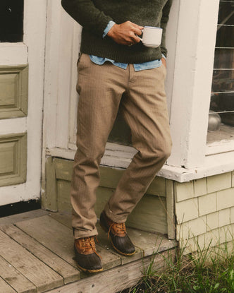 fit model leaning against the wall wearing The Emlen Pant in Khaki Herringbone