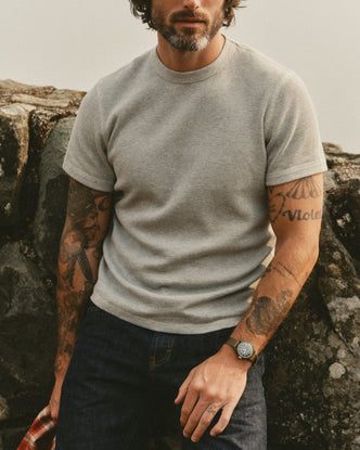 fit model leaning against a wall wearing The Organic Cotton Short Sleeve Crew in Heather Grey Waffle