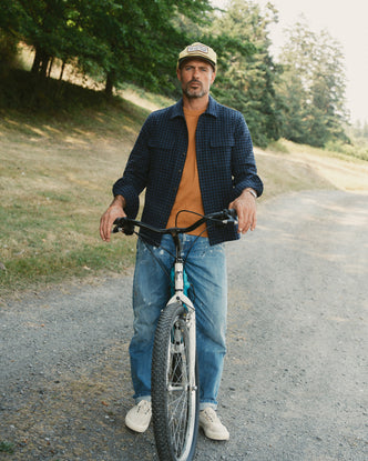 fit model on a bike wearing The Shore Shirt in Midnight Check Wool