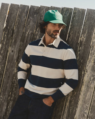 fit model leaning against the wall wearing The Rugby Shirt in Navy Stripe