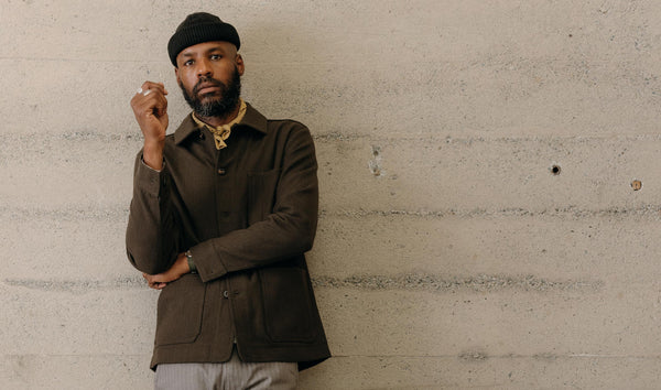 fit model leaning against the wall wearing The Ojai Jacket in Army Herringbone Wool
