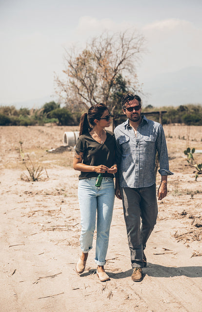 A couple talking and walking through a dry field.