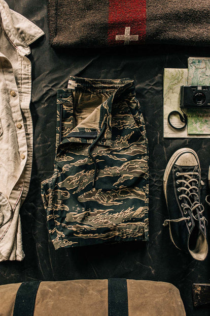 A flatlay of an outfit, including our Adventure Short in Tiger Camo, with a map and camera.