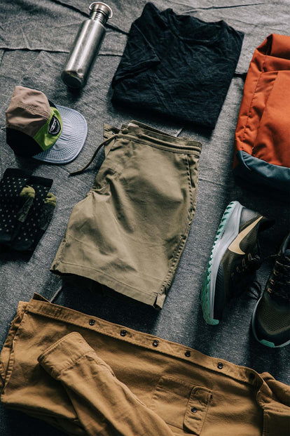 A flatlay of an outfit, including our Adventure Short in Olive, with hiking shoes.