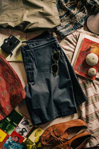 A flatlay of an outfit, including our The Adventure Short in Coal, alongside some outdoor gear.