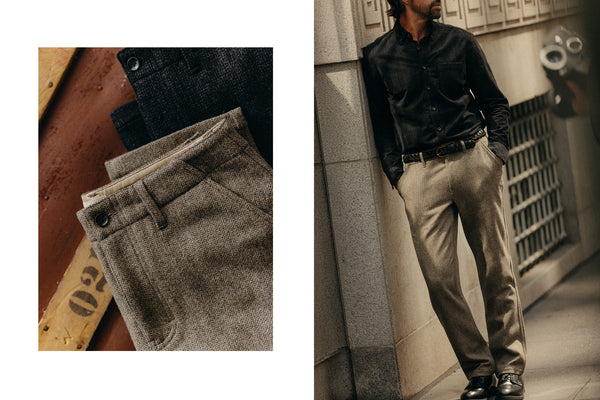 fit model leaning against the wall wearing The Carnegie Pant in Gravel Herringbone