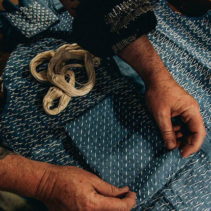 A pair of hands grasp a swatch of textured blue fabric.