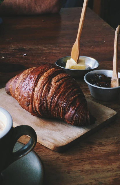 A croissant and fixings on a chopping board.