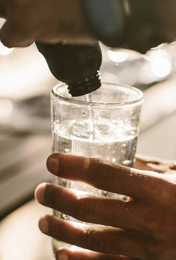 Close up on water being poured out of a bottle into a glass.