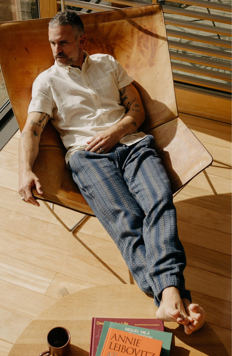 fit model sitting in a chair wearing The Apres Pant in Marine Stripe