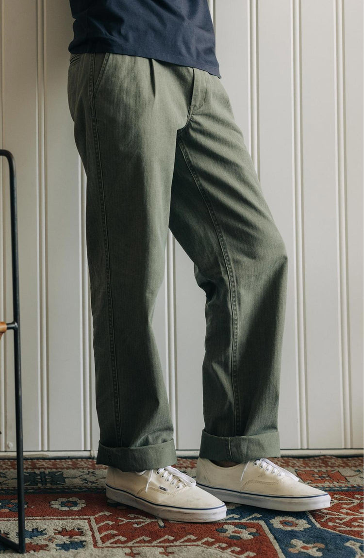 fit model leaning against the wall wearing The Matlow Pant in Dried Sage Pigment Herringbone