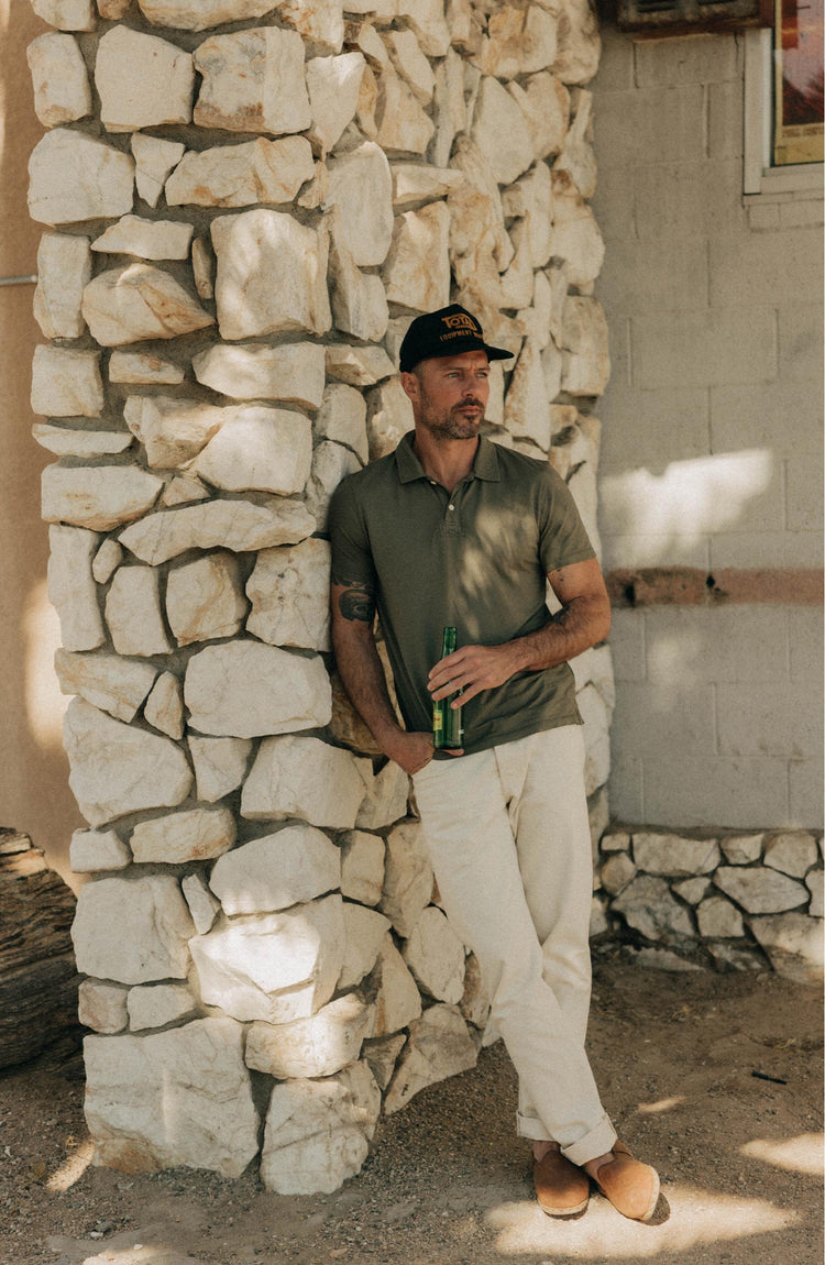 fit model leaning against the wall wearing The Cotton Hemp Polo in Olive