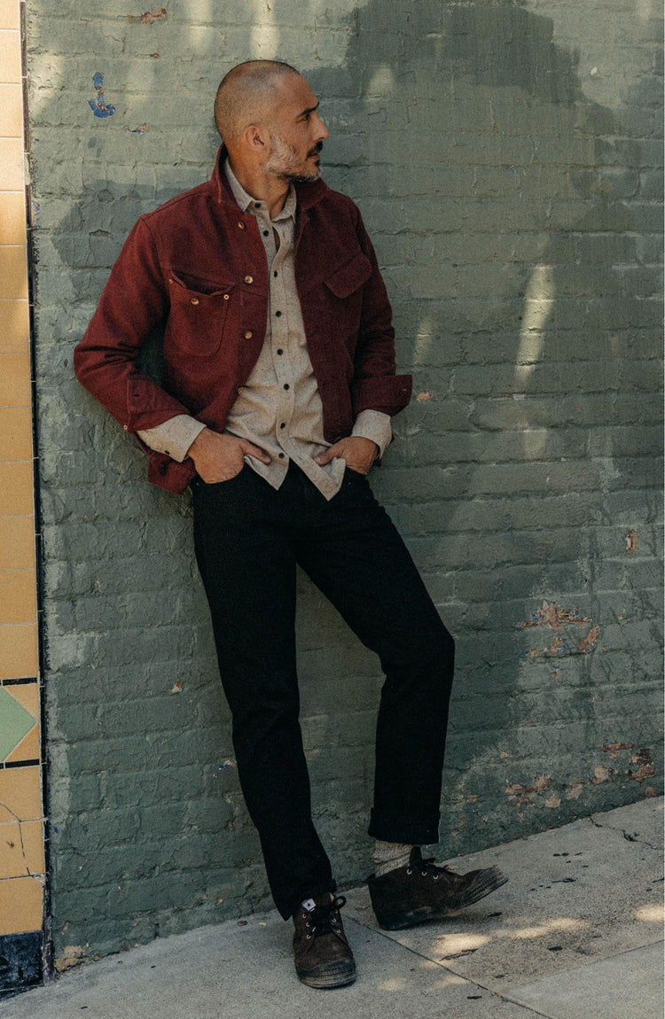 fit model leaning against the wall wearing The Long Haul Jacket in Dried Cherry Moleskin
