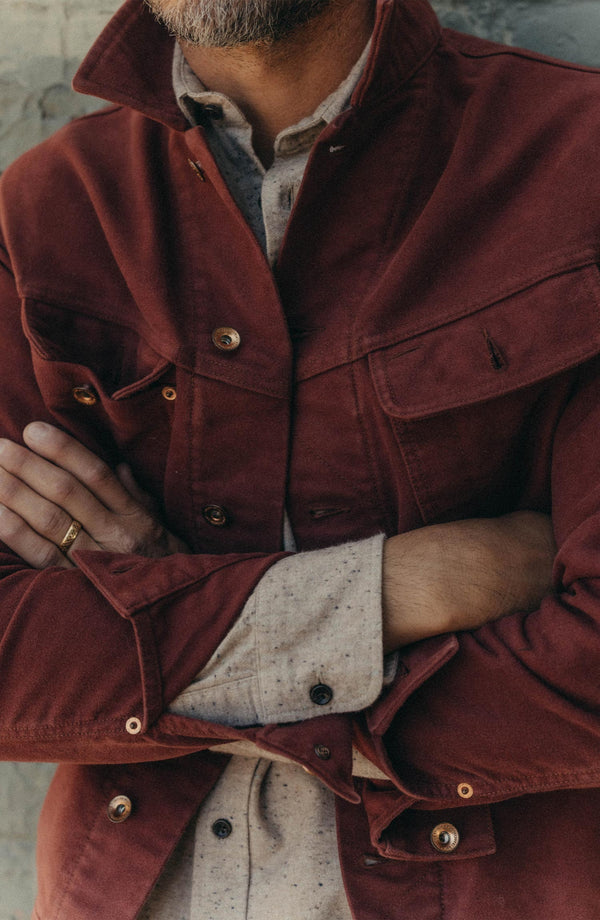 fit model with his arms crossed wearing The Long Haul Jacket in Dried Cherry Moleskin