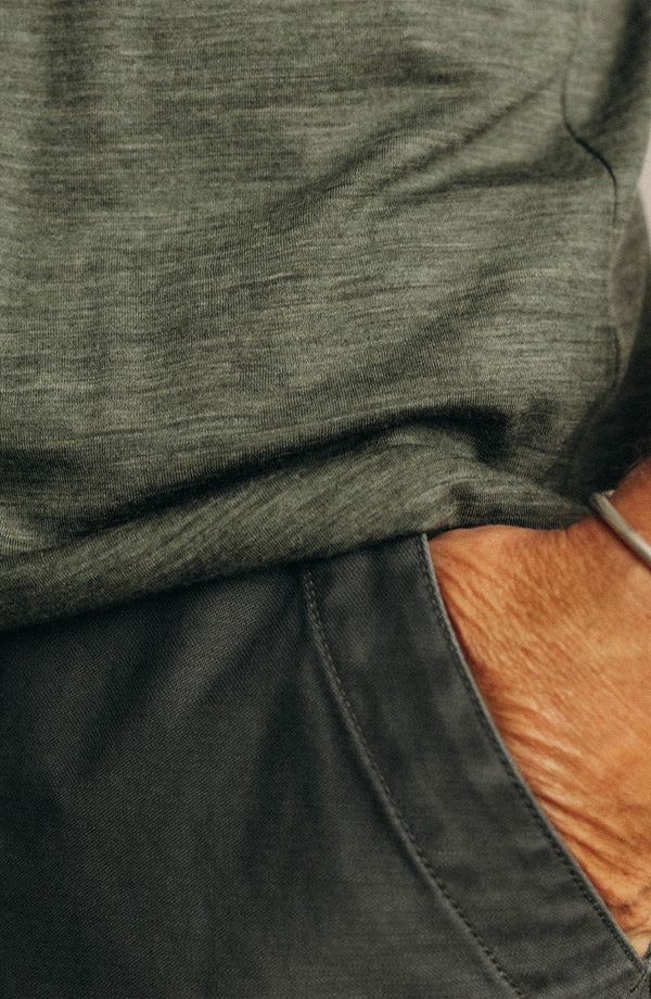 fit model lying on the ground wearing The Merino Tee in Heather Army