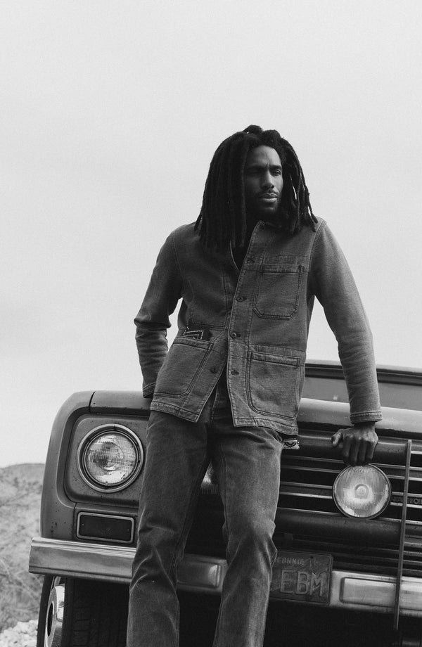 fit model leaning against the car wearing The Primer Jacket in Washed Indigo Terry