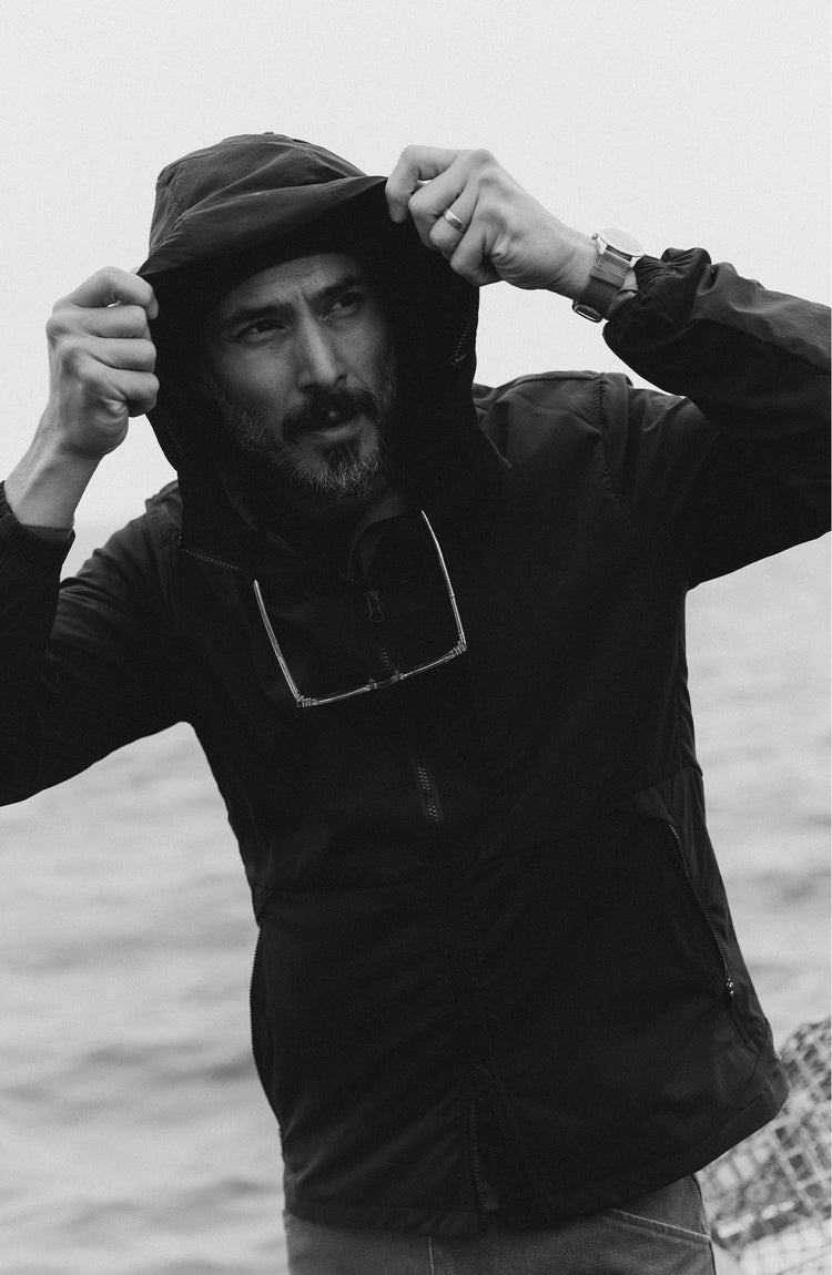 fit model picking up a crab wearing The Ridgeline Jacket in Coal