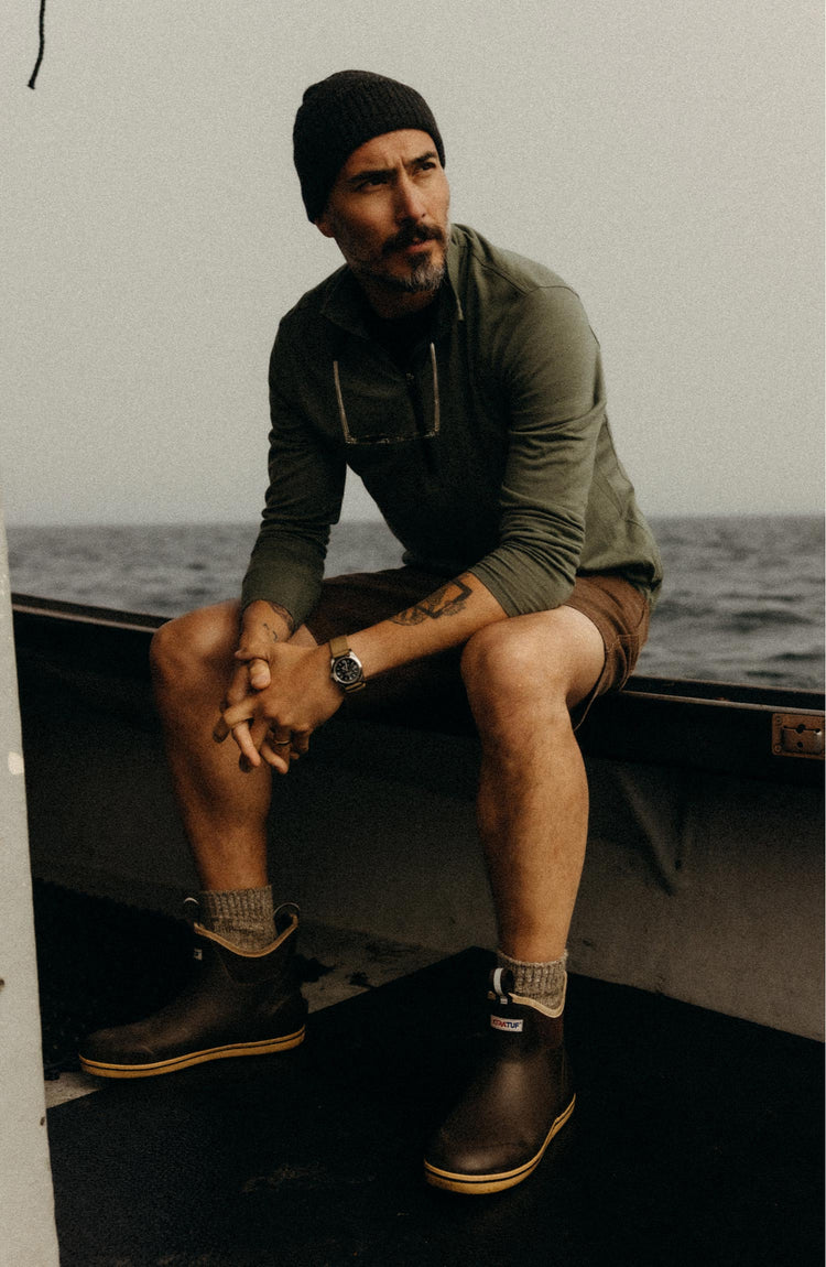fit model sitting wearing The Ridgeline Merino Half Zip in Field Olive