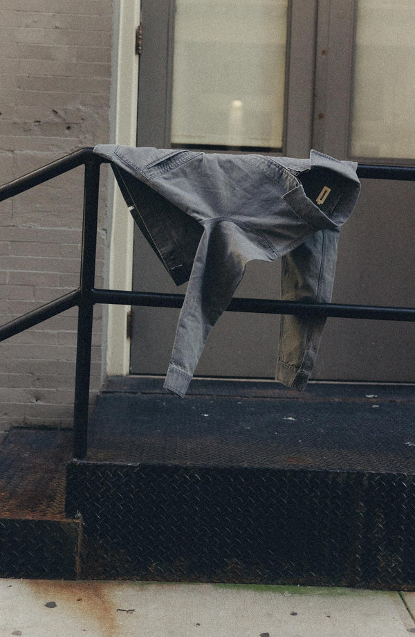 editorial image of The Shifter Jacket in Dark Grey Pigment Canvas on a railing
