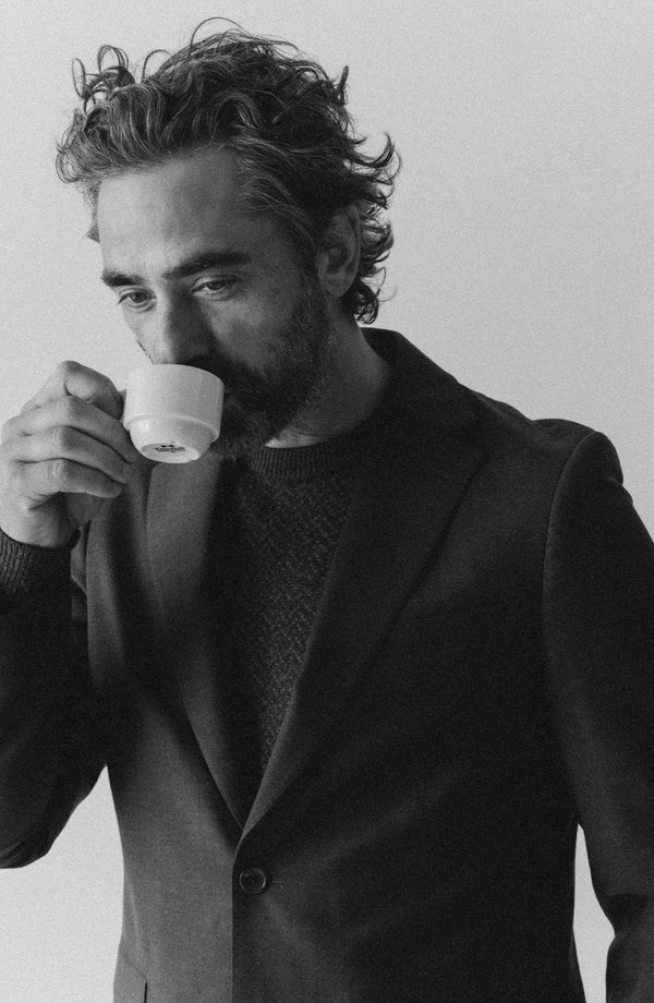 fit model taking a sip wearing The Stevens Sportcoat in Black Olive Wool Flannel