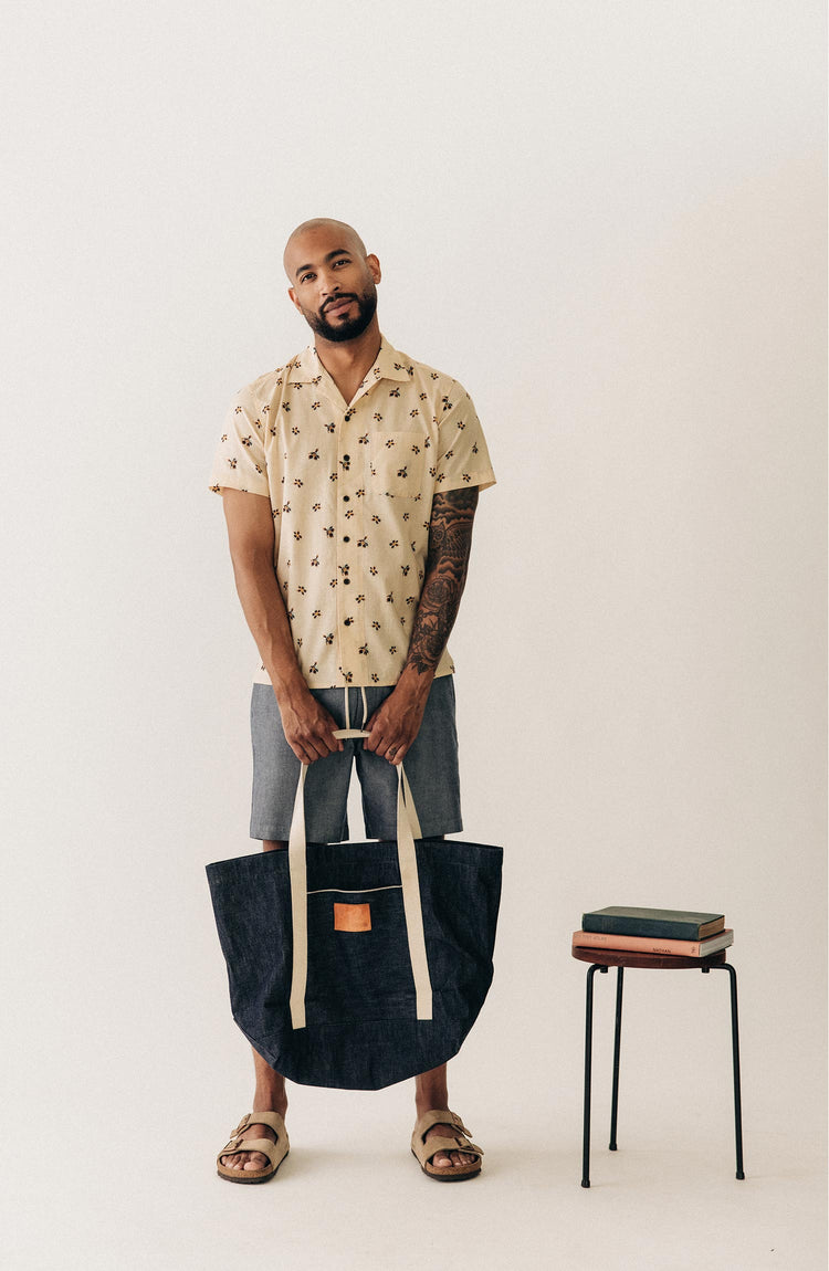 fit model holding a bag wearing The Apres Short in Indigo Chambray