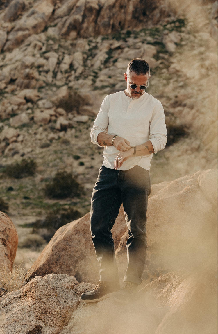 fit model standing on a rock wearing The Camp Pant in Coal Chipped Canvas