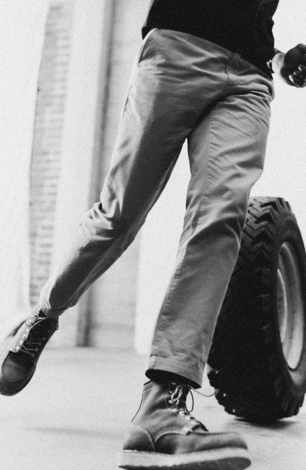 A pair of Foundation Pants folded on a black background, showing the back pocket.