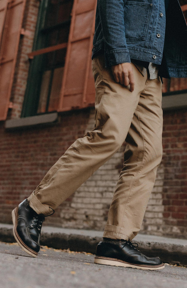 A pair of Foundation Pants folded on a black background, showing the back pocket.