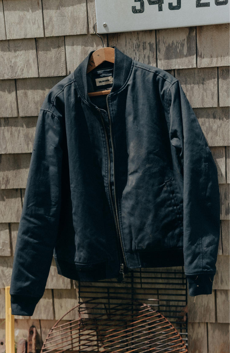 editorial image of The Insulated Bomber Jacket in Dark Navy Dry Wax hanging
