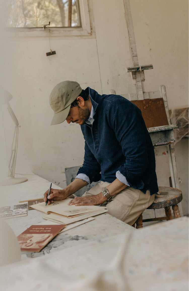 fit model sitting wearing The Long Sleeve Polo in Indigo Knit Stripe
