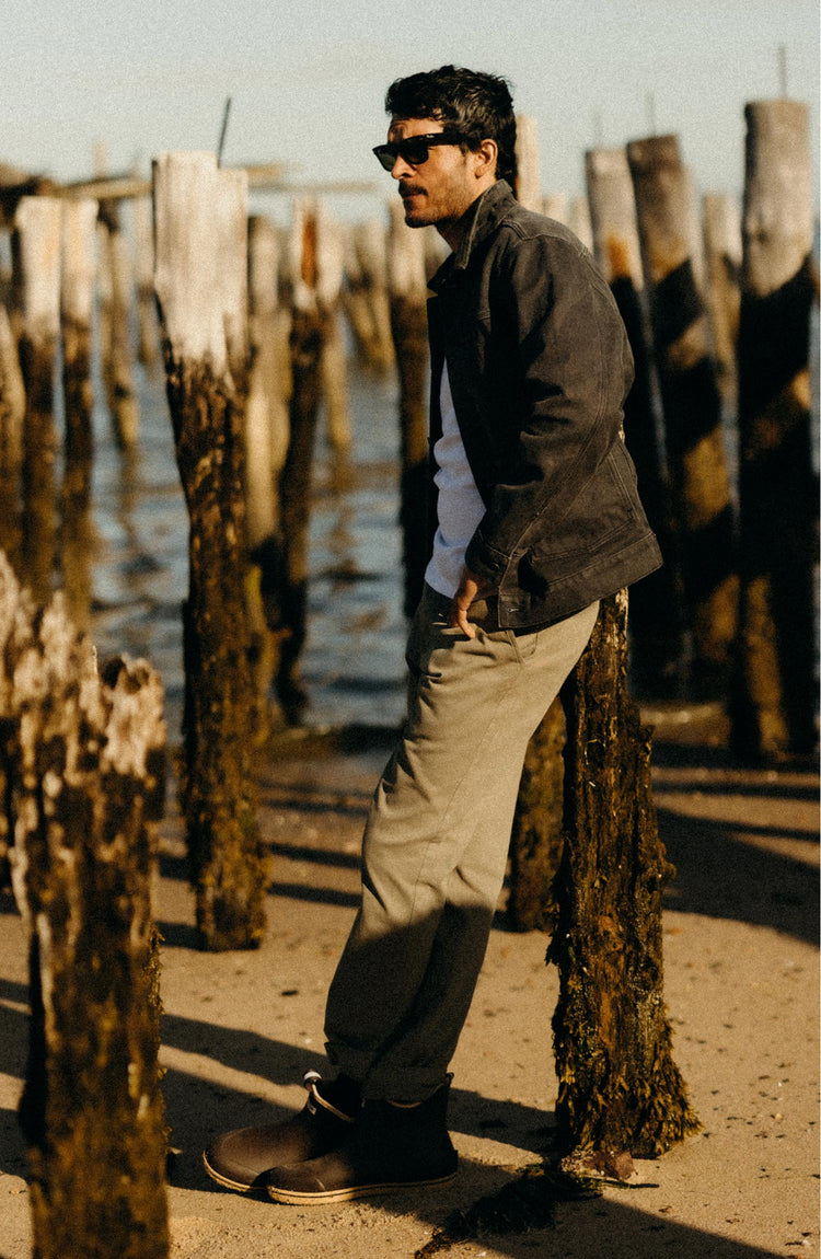 fit model leaning against a stick wearing The Ryder Jacket in Coal Chipped Canvas