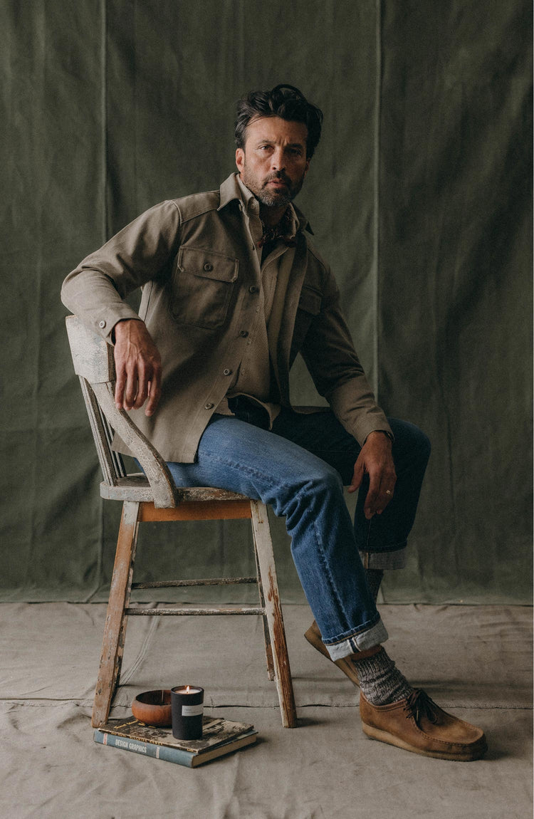 fit model leaning against a chair wearing The Straight Jean in Mid Wash Organic Selvedge