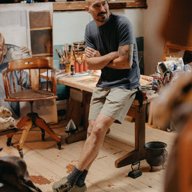 fit model sitting on a work desk wearing The Apres Trail Short in Light Sage Slub