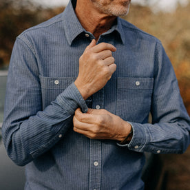 fit model adjusting cuffs of The Utility Shirt in Washed Indigo Herringbone