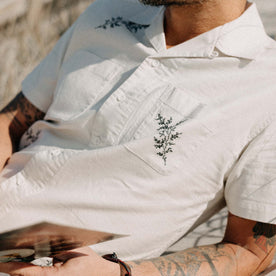 fit model lying on the beach wearing The Conrad Shirt in Seaside Embroidery