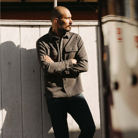 fit model leaning against the wall wearing The Ledge Shirt in Shale Twill