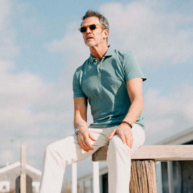 fit model sitting on a bench wearing The Organic Cotton Polo in Washed Indigo