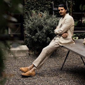 fit model sitting wearing The Loafer in Tan Suede