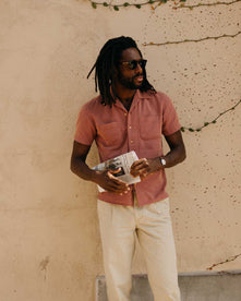 fit model leaning against the wall wearing The Conrad Shirt in Fired Brick Dobby