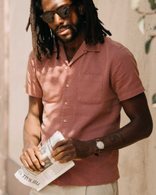 fit model holding a newspaper wearing The Conrad Shirt in Fired Brick Dobby