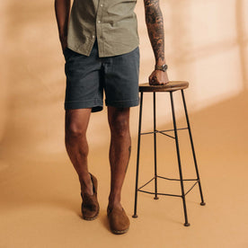 fit model leaning on a stool wearing The Matlow Short in Dark Navy Herringbone