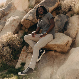 fit model sitting on a rock wearing The Short Sleeve California in Heather Slate Cord