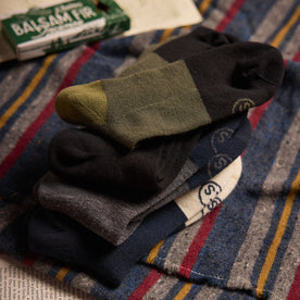 editorial image of The Merino Sock in Olive and other socks stacked on top of each other