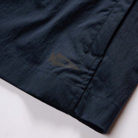 material shot of the brand tag on The Deploy Packable Shell in Dark Navy