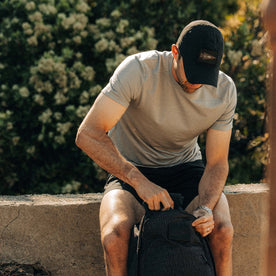 fit model zipping up a backpack wearing The Performance TAC Hat in Black