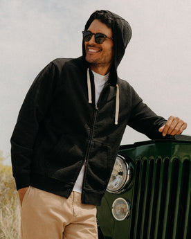 fit model leaning against a car wearing The Apres Zip Hoodie in Black Indigo Terry, Knits by Taylor Stitch